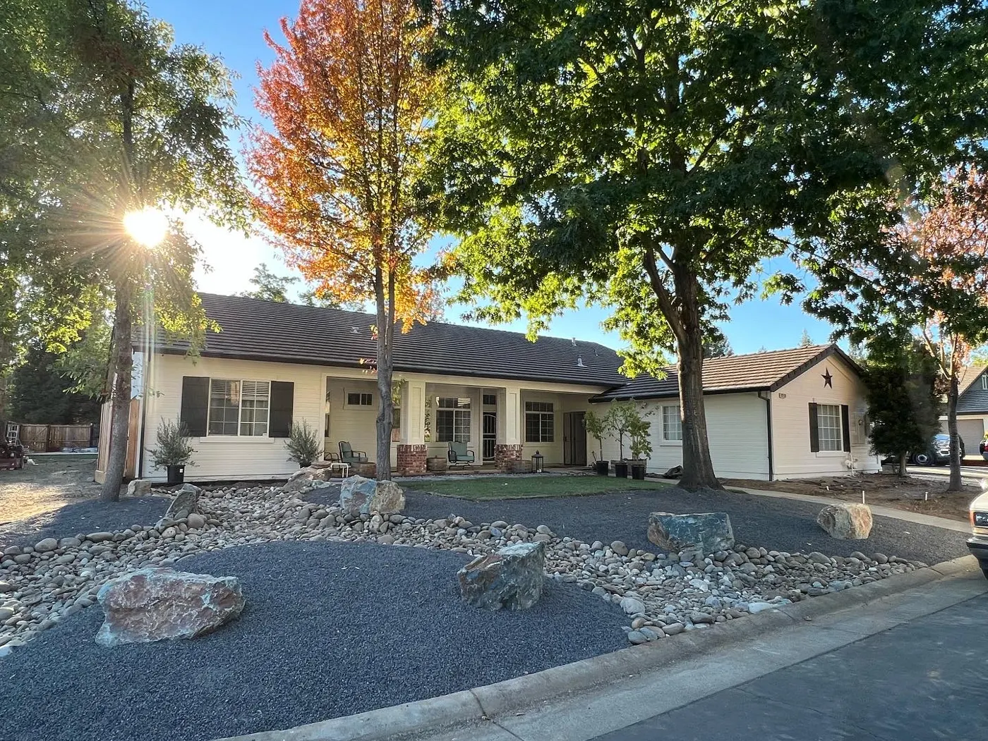 Single-story ranch home with rock landscaping and autumn trees